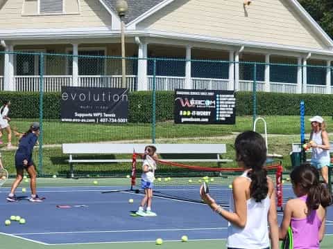 a group of kids playing tennis