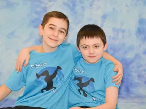 two boys lying on a blue blanket
