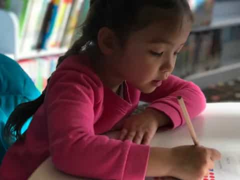 a young girl writing on a book