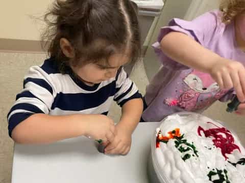 a couple of girls sit near a cake