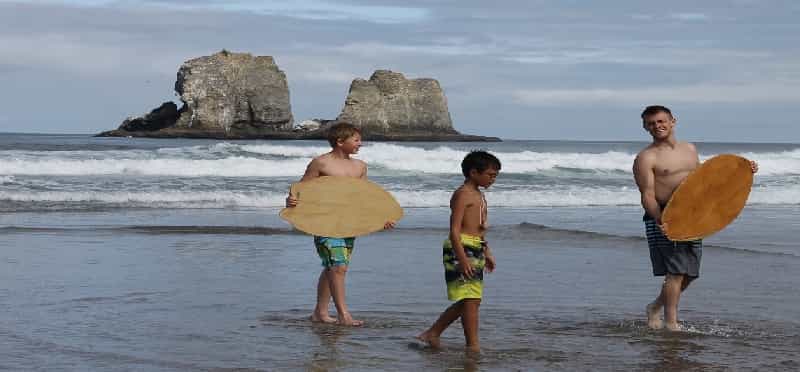 a group of boys carrying surfboards on a beach