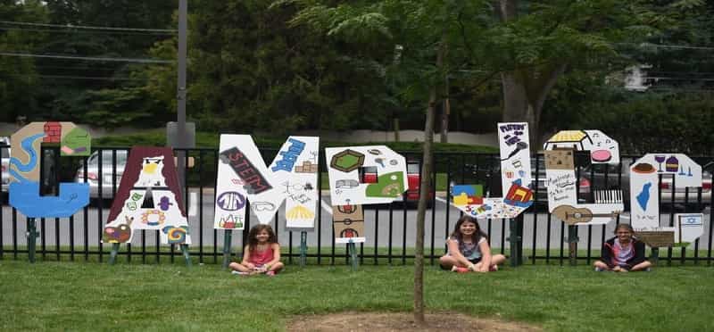 a group of people sitting on the grass by a sign