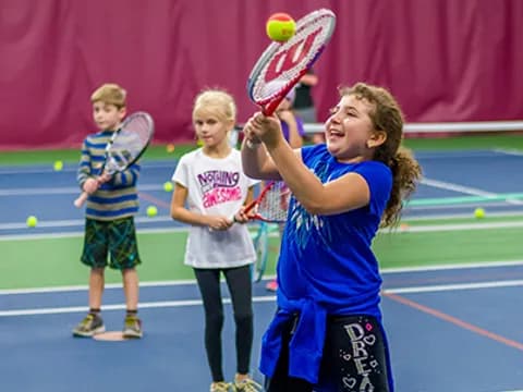 a group of kids playing tennis