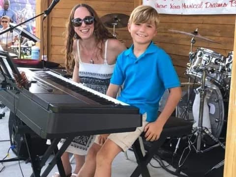 a boy and girl sitting at a piano
