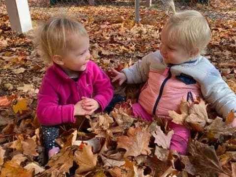 two children playing in leaves