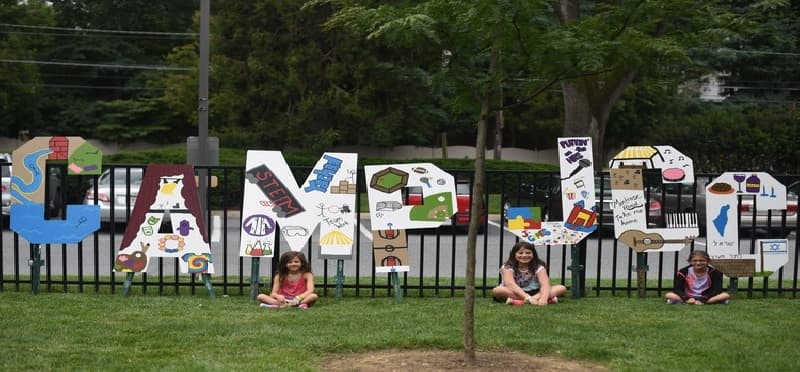 a group of people sitting on the grass by a sign