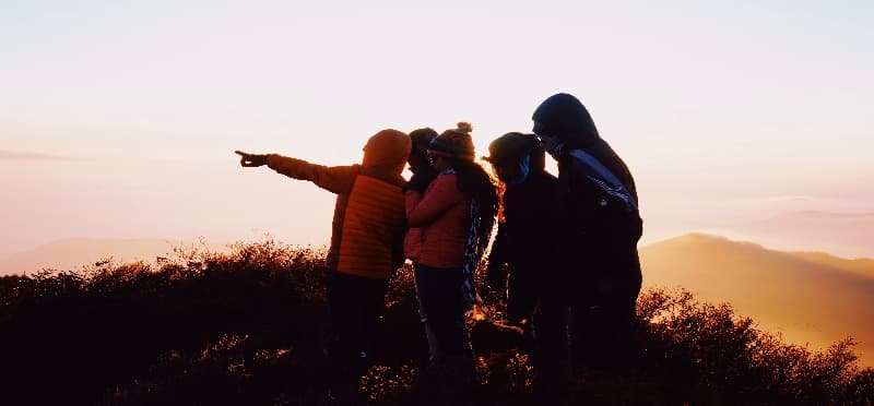 a group of people standing on a hill with their arms raised