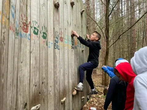 a boy climbing a wooden fence