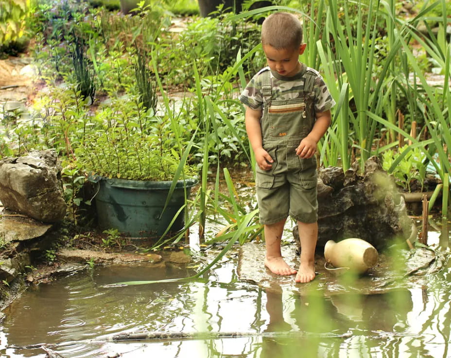 a boy standing in a pond