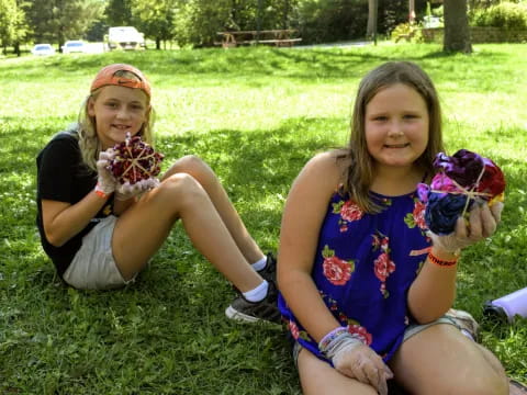 two girls sitting on grass