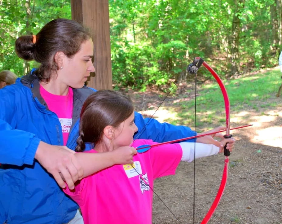 a person helping a child with a bow