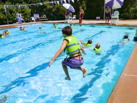 a boy jumping into a pool