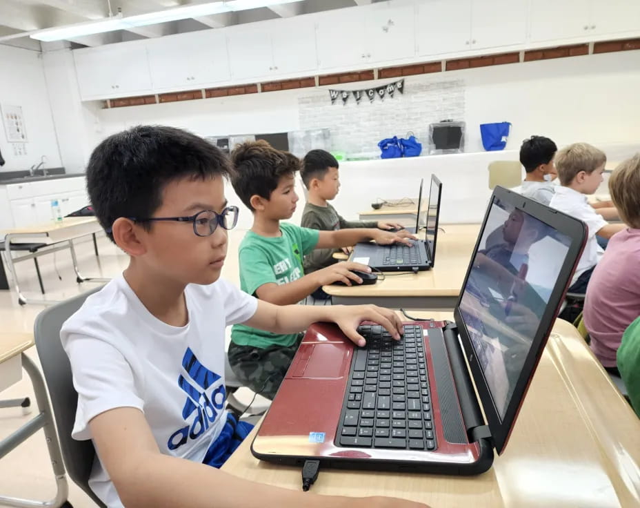 a group of children using laptops