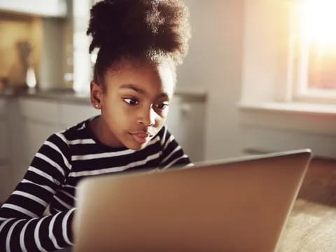 a young boy looking at a laptop