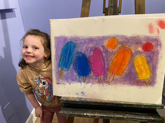 a child standing next to a painting
