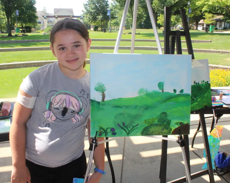 a boy standing next to a painting
