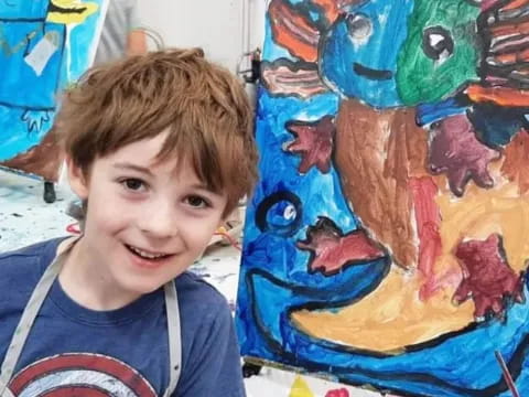 a boy smiling next to a painting
