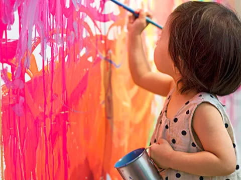 a young girl painting a wall