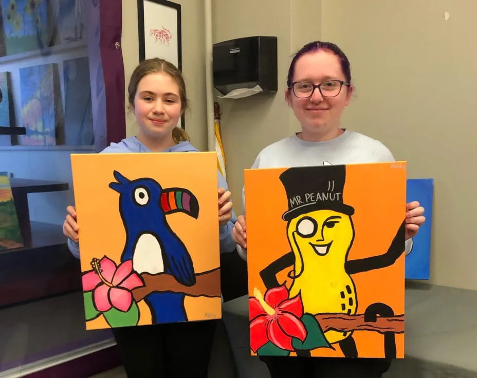 a man and a woman holding paintings