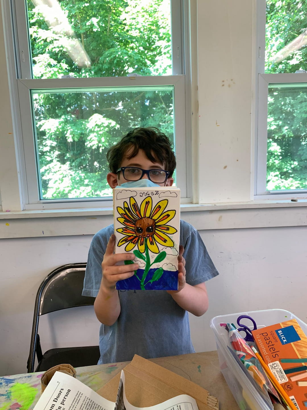 a boy sitting at a table with a book and a window