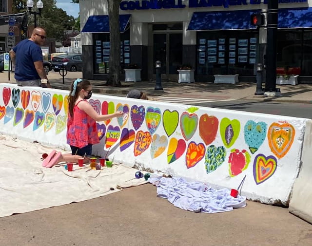 a girl painting on a sidewalk