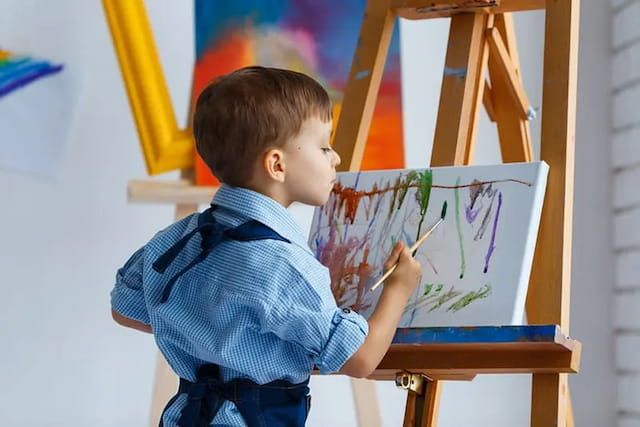 a young boy drawing on a white board