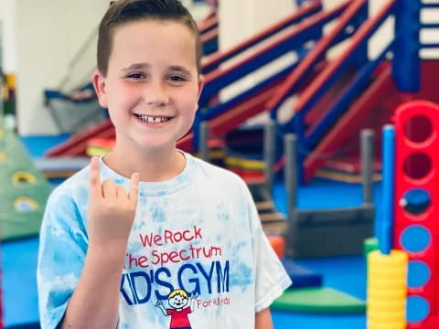 a boy smiling with his thumbs up