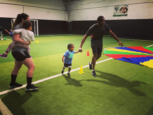 a man and a woman running on a field with a child
