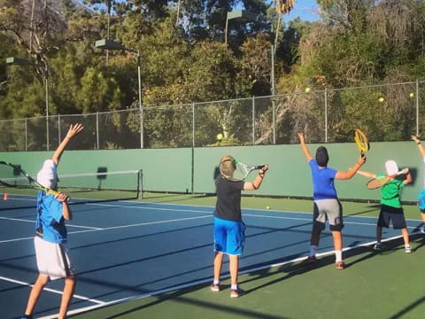 a group of kids playing tennis