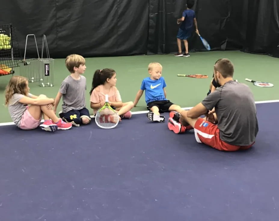 a group of kids playing tennis