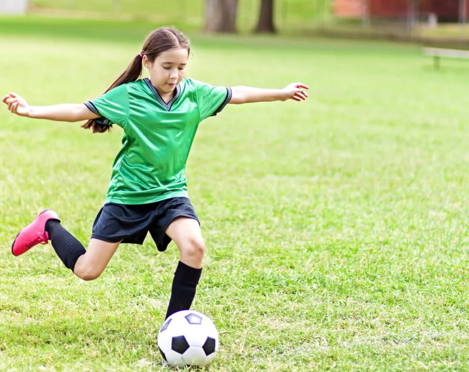 a girl kicking a football ball
