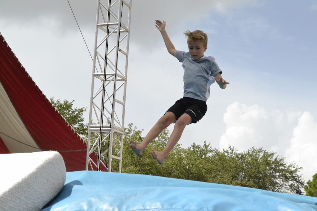 a boy jumping off a trampoline