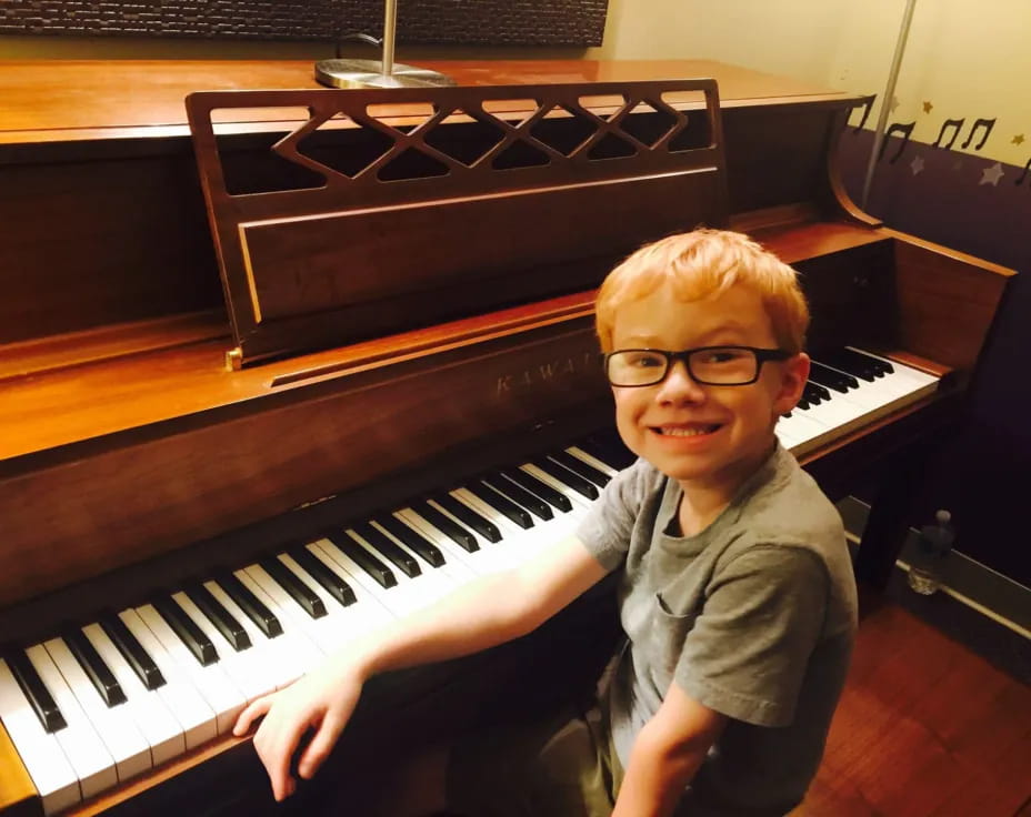 a boy sitting at a piano