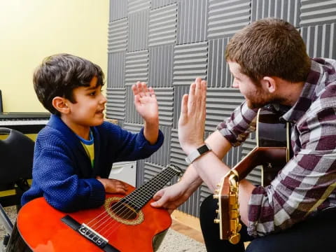 a man playing guitar to a boy