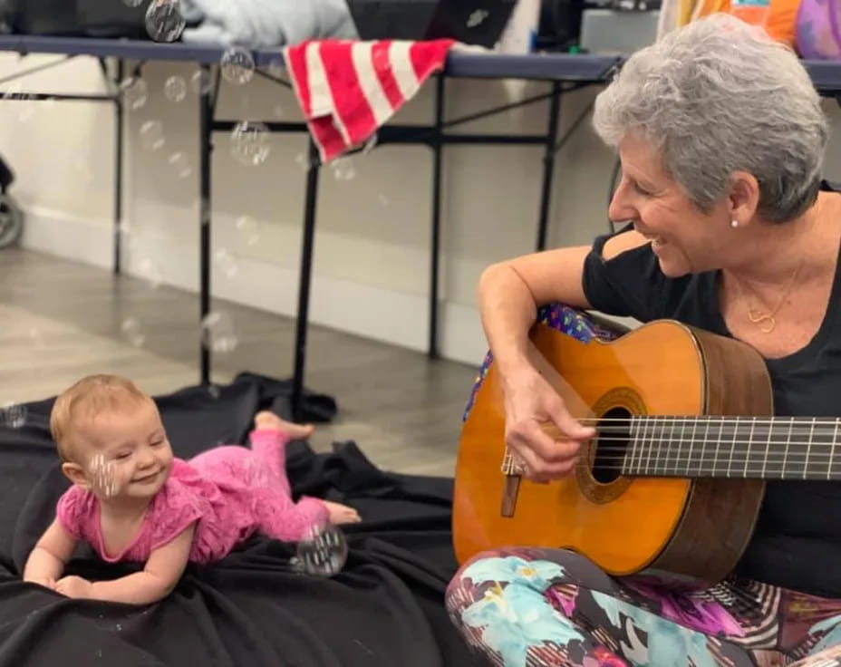 a man playing guitar next to a baby
