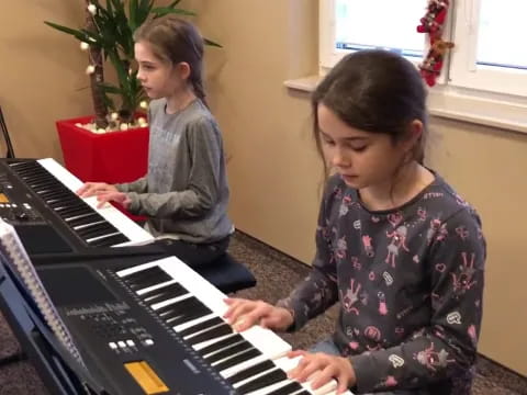 a couple of girls playing piano