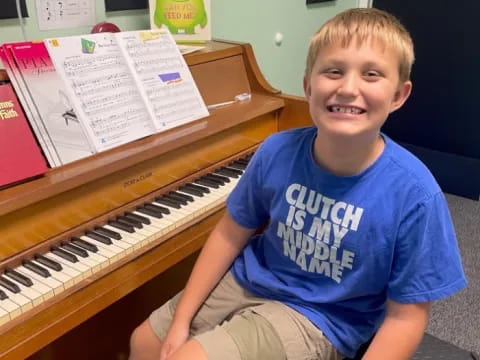 a boy sitting next to a piano