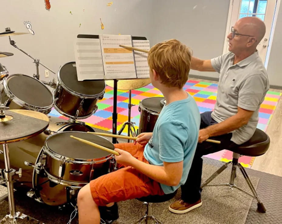 a person and a boy playing drums