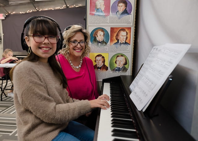 a couple of women holding a piano