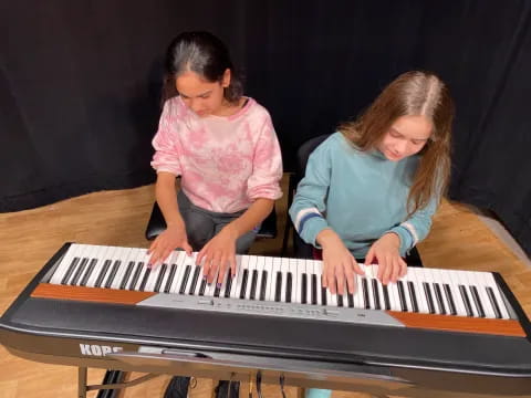 a couple of girls playing piano