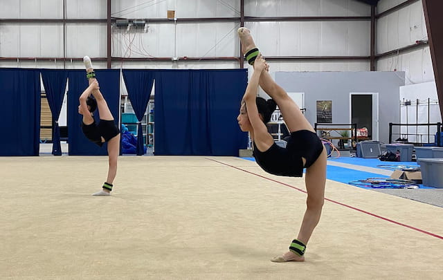 a couple of people doing a handstand in a gym