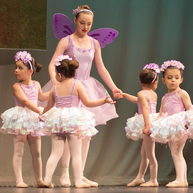 a group of girls wearing dresses and dancing