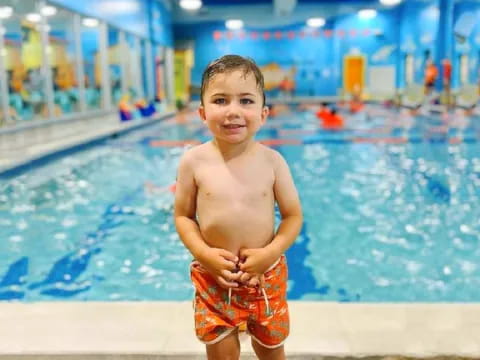 a boy standing by a pool