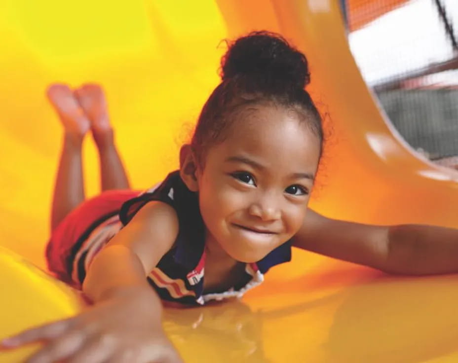 a child lying on a yellow slide