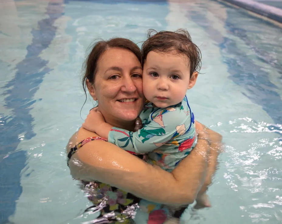 a person holding a baby in a pool