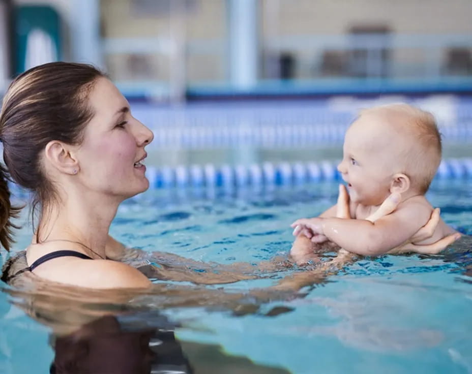 a woman holding a baby in a pool