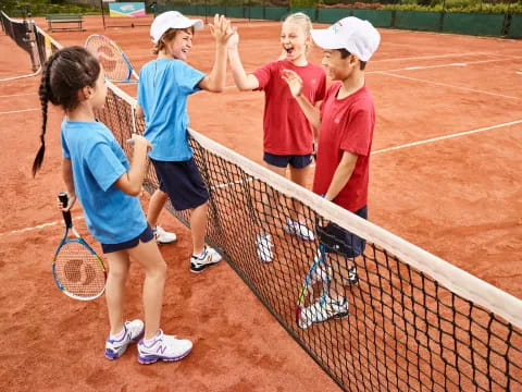 a group of kids playing tennis