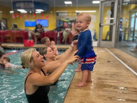 a person holding a baby in a pool