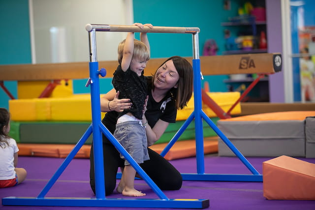 a woman holding a girl on a bar