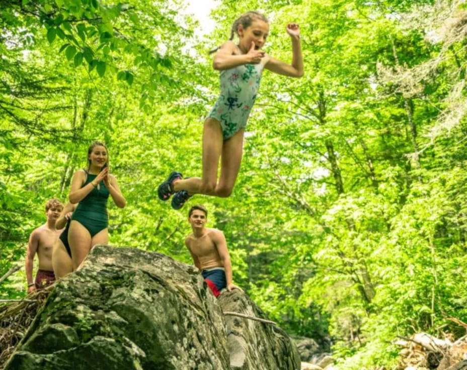 a group of kids jumping off a rock